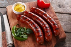 Salchicha asada a la parrilla en un tablero de madera con la salsa y las verduras Fotos de archivo libres de regalías