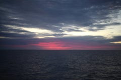 Salida del sol colorida roja hermosa en el mar con las nubes dramáticas y el sol que brillan foto de archivo Salida del sol colorida roja hermosa en el mar con las nubes dramáticas y el sol que brillan foto de archivo