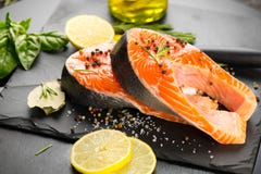 Salmon. Raw trout fish steak with herbs and lemon on black slate background. Cooking royalty free stock photo Salmon. Raw trout fish steak with herbs and lemon on black slate background. Cooking royalty free stock photo