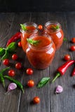 Salsa de la salsa de tomate de tomate con los tomates de cereza y pimientas de chile, ajo e hierbas candentes en un tarro de cris imagen de archivo libre de regalías Salsa de la salsa de tomate de tomate con los tomates de cereza y pimientas de chile, ajo e hierbas candentes en un tarro de cris imagen de archivo libre de regalías