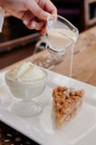 Salsa di versamento della vaniglia sulla torta della briciola della mela con il gelato immagine stock libera da diritti Salsa di versamento della vaniglia sulla torta della briciola della mela con il gelato immagine stock libera da diritti