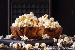 Saltat popcorn i en tr?bunke, sjuklig mat, m?rk tr?k?ksbordbakgrund, selektiv fokus arkivbilder Saltat popcorn i en tr?bunke, sjuklig mat, m?rk tr?k?ksbordbakgrund, selektiv fokus arkivbilder