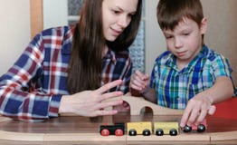 Samen het spelen Het mamma en de zoon spelen een houten spoorweg met trein, wagens en tunnelzitting bij de lijst royalty-vrije stock afbeelding Samen het spelen Het mamma en de zoon spelen een houten spoorweg met trein, wagens en tunnelzitting bij de lijst royalty-vrije stock afbeelding