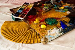 Sammansättning av en konstnärlig palett, en handfan, vattenfärger, akryler, en spatel, en genomskinlig boll och pastell Arkivfoto Sammansättning av en konstnärlig palett, en handfan, vattenfärger, akryler, en spatel, en genomskinlig boll och pastell Arkivfoto