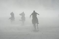Sand storm horse riders mount bromo