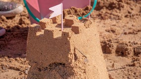 Sandslott som omges av strandleksaker royaltyfri bild Sandslott som omges av strandleksaker royaltyfri bild