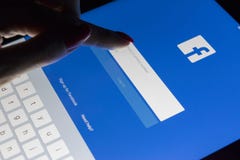 A woman`s hand is touching screen on tablet Apple iPad Pro at night with Facebook homepage webpage. Facebook the biggest social stock photography A woman`s hand is touching screen on tablet Apple iPad Pro at night with Facebook homepage webpage. Facebook the biggest social stock photography