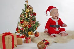 Santa Baby med julgranen arkivfoto Santa Baby med julgranen arkivfoto