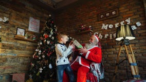 Santa Claus framlägger gåvan till den lyckliga pojken arkivfoton Santa Claus framlägger gåvan till den lyckliga pojken arkivfoton