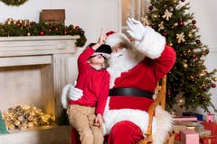 Santa Claus och unge i vrhörlurar med mikrofon fotografering för bildbyråer Santa Claus och unge i vrhörlurar med mikrofon fotografering för bildbyråer