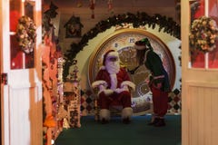 Santa Claus s'asseyant dans son elfe de fauteuil et d'aide image libre de droits Santa Claus s'asseyant dans son elfe de fauteuil et d'aide image libre de droits
