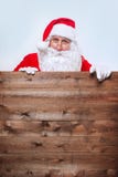 Santa Claus se dirigeant dans la bannière en bois de publicité de blanc avec l'espace de copie photographie stock libre de droits Santa Claus se dirigeant dans la bannière en bois de publicité de blanc avec l'espace de copie photographie stock libre de droits