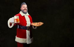 Santa con pizza e un vetro di birra in sue mani al Natale immagine stock libera da diritti Santa con pizza e un vetro di birra in sue mani al Natale immagine stock libera da diritti