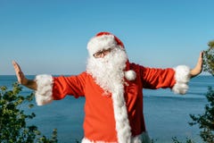 Santa doing exercises on the ocean. Traditional red outfit and relaxing on the beach stock photos Santa doing exercises on the ocean. Traditional red outfit and relaxing on the beach stock photos