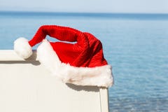 Santa Hat Hanging sulla sedia di spiaggia. fotografia stock Santa Hat Hanging sulla sedia di spiaggia. fotografia stock