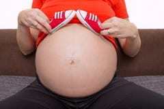 Sapatas pequenas para o bebê por nascer na barriga da mulher gravida imagem de stock Sapatas pequenas para o bebê por nascer na barriga da mulher gravida imagem de stock