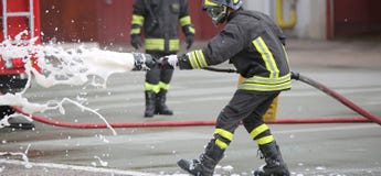 Sapeurs-pompiers tout en s'éteignant le feu avec la mousse photos libres de droits Sapeurs-pompiers tout en s'éteignant le feu avec la mousse photos libres de droits