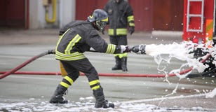 Sapeurs-pompiers tout en s'éteignant le feu avec la mousse photographie stock libre de droits Sapeurs-pompiers tout en s'éteignant le feu avec la mousse photographie stock libre de droits