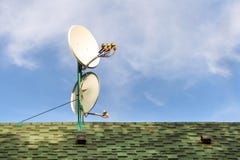 Satellite dish antennas on rooftop of private house covered with shingle tile. Blue sky on bright sunny day on stock photo Satellite dish antennas on rooftop of private house covered with shingle tile. Blue sky on bright sunny day on stock photo