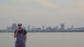Satisfied construction worker drinks coffee or tea near the evening city stock video footage Satisfied construction worker drinks coffee or tea near the evening city stock video footage
