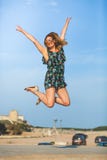 Saut de bonheur La jeune femme joyeuse et souriante saute avec des bras augmentés photos libres de droits Saut de bonheur La jeune femme joyeuse et souriante saute avec des bras augmentés photos libres de droits