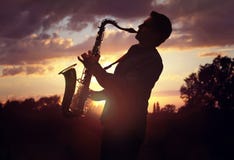 Saxophonist, der Saxophon gegen Sonnenuntergang spielt lizenzfreies stockbild Saxophonist, der Saxophon gegen Sonnenuntergang spielt lizenzfreies stockbild