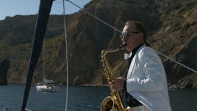 Saxophonist στην άσπρη τζαζ παιχνιδιού κοστουμιών στο χρυσό saxophone απόθεμα βίντεο Saxophonist στην άσπρη τζαζ παιχνιδιού κοστουμιών στο χρυσό saxophone απόθεμα βίντεο