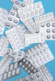 Scattered various pills in gray packaging on a blue background Royalty Free Stock Photography Scattered various pills in gray packaging on a blue background Royalty Free Stock Photography