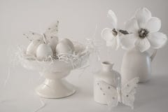 Scena d'annata bianca di Pasqua, supporto del dolce con le uova, vasi, fiori, contro fondo bianco immagine stock libera da diritti Scena d'annata bianca di Pasqua, supporto del dolce con le uova, vasi, fiori, contro fondo bianco immagine stock libera da diritti