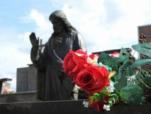 Scena w cmentarzu: gałąź sfałszowani czerwoni kwiaty W tle, statua zamazująca jezus chrystus obraz royalty free Scena w cmentarzu: gałąź sfałszowani czerwoni kwiaty W tle, statua zamazująca jezus chrystus obraz royalty free