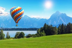 Scenic summer landscape with hot air balloon, lake and mountains