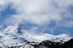 Sceniczna śnieżna góra stronniczo zakrywająca mgłami z niebieskim niebem w tle zdjęcie stock Sceniczna śnieżna góra stronniczo zakrywająca mgłami z niebieskim niebem w tle zdjęcie stock