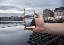 Sceniczny widok most i budynki stara grodzka ręka z smartphone na ekranie dziejowy centrum Praga, Charles, z czego obraz stock Sceniczny widok most i budynki stara grodzka ręka z smartphone na ekranie dziejowy centrum Praga, Charles, z czego obraz stock