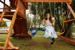 Sch?ne Familie hat Spa? drau?en Eltern mit den Kindern, die auf ein Schwingen fahren Mutter spielt mit ihrem wenigen Sohn auf ein stockbild Sch?ne Familie hat Spa? drau?en Eltern mit den Kindern, die auf ein Schwingen fahren Mutter spielt mit ihrem wenigen Sohn auf ein stockbild