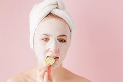 Sch?ne junge Frau wendet eine kosmetische Gewebemaske auf einem Gesicht auf einem rosa Hintergrund an Gesundheitswesen- und Sch?n lizenzfreies stockbild Sch?ne junge Frau wendet eine kosmetische Gewebemaske auf einem Gesicht auf einem rosa Hintergrund an Gesundheitswesen- und Sch?n lizenzfreies stockbild