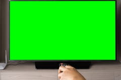 Schermo verde TV con il telecomando defocused della tenuta della mano fotografia stock Schermo verde TV con il telecomando defocused della tenuta della mano fotografia stock