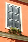 Schilderachtig uitstekend venster met gesneden houten zonneblinden en bloemen in heldere oranje muur stock afbeeldingen Schilderachtig uitstekend venster met gesneden houten zonneblinden en bloemen in heldere oranje muur stock afbeeldingen