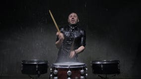 Schlagzeuger, der Trommeln mit Wasser in einem dunklen Studio spielt stock footage Schlagzeuger, der Trommeln mit Wasser in einem dunklen Studio spielt stock footage
