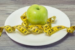 Schließen Sie herauf das Foto des Maßbandes umwickelt um einen Apfel auf weißem p lizenzfreies stockbild Schließen Sie herauf das Foto des Maßbandes umwickelt um einen Apfel auf weißem p lizenzfreies stockbild