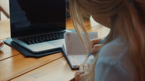 Schließen Sie herauf die Ansicht der Geschäftsfrau arbeitend mit Notizbuch und Laptop stock video footage Schließen Sie herauf die Ansicht der Geschäftsfrau arbeitend mit Notizbuch und Laptop stock video footage