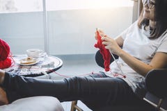 Schließen Sie herauf Schuss von den Händen der jungen Frau, die zu Hause ein rotes Schalhandwerk im Wohnzimmer auf Terrasse stric lizenzfreie stockfotografie Schließen Sie herauf Schuss von den Händen der jungen Frau, die zu Hause ein rotes Schalhandwerk im Wohnzimmer auf Terrasse stric lizenzfreie stockfotografie