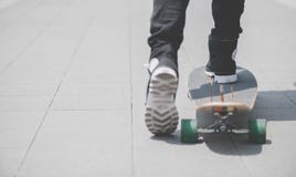 Schließen Sie oben vom skater& x27; s-Beine auf dem longboard Reiten an der Straße herein draußen stockfotografie Schließen Sie oben vom skater& x27; s-Beine auf dem longboard Reiten an der Straße herein draußen stockfotografie