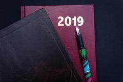 Schließen Sie oben von 2019 rot und von den braunen ledernen diarys mit Füllfederhalter stockbild Schließen Sie oben von 2019 rot und von den braunen ledernen diarys mit Füllfederhalter stockbild