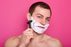 Schließen Sie oben vom hübschen hemdlosen Mann steht lokalisiert über rosa Hintergrund Kerl mit nackten Schultern hält Rasiermess lizenzfreies stockbild Schließen Sie oben vom hübschen hemdlosen Mann steht lokalisiert über rosa Hintergrund Kerl mit nackten Schultern hält Rasiermess lizenzfreies stockbild