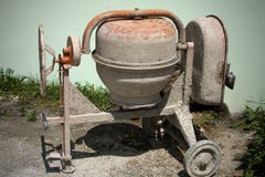 Schmutziger Minibetonmischer im Boden mit Little Rock und Steinen und in den hohen grünen Gräsern hinter ihm Eben benutzte Ausrüs stockbild Schmutziger Minibetonmischer im Boden mit Little Rock und Steinen und in den hohen grünen Gräsern hinter ihm Eben benutzte Ausrüs stockbild