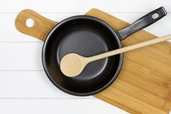 Schneidebrett mit Bratpfanne und hölzernem Löffel lizenzfreies stockbild Schneidebrett mit Bratpfanne und hölzernem Löffel lizenzfreies stockbild