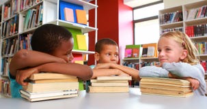 School kids leaning on stack of books in library stock video footage School kids leaning on stack of books in library stock video footage