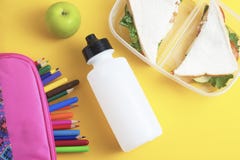 School lunch sandwich and green apple, bottle of water, healthy eating concept, colorfu encils yellow background, top view with co stock image School lunch sandwich and green apple, bottle of water, healthy eating concept, colorfu encils yellow background, top view with co stock image