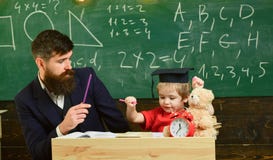 Schoolboy doing hometask with father and writting in workbook, chalkboard on background. Father checking hometask, helps royalty free stock photo Schoolboy doing hometask with father and writting in workbook, chalkboard on background. Father checking hometask, helps royalty free stock photo
