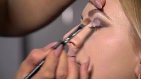 Schoonheidszaal Het jonge mooie meisjesmodel zit als voorzitter De make-upkunstenaar maakt meisjesmake-up Make-upkunstenaar stock video Schoonheidszaal Het jonge mooie meisjesmodel zit als voorzitter De make-upkunstenaar maakt meisjesmake-up Make-upkunstenaar stock video